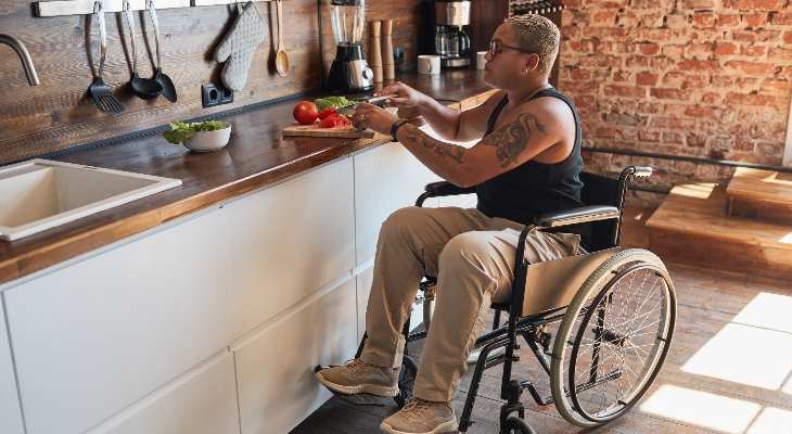 Woman in a wheelchair preparing vegetables in kitchen.