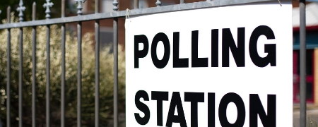 Polling station sign attached to railings.