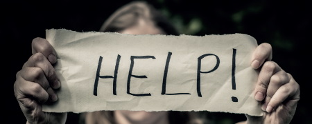 Person holding help sign in front of their face.