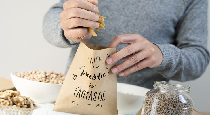 A person filling a paper bag with grains.