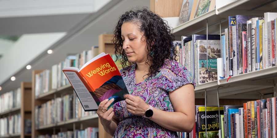 Library visitor reading Weaving Words.
