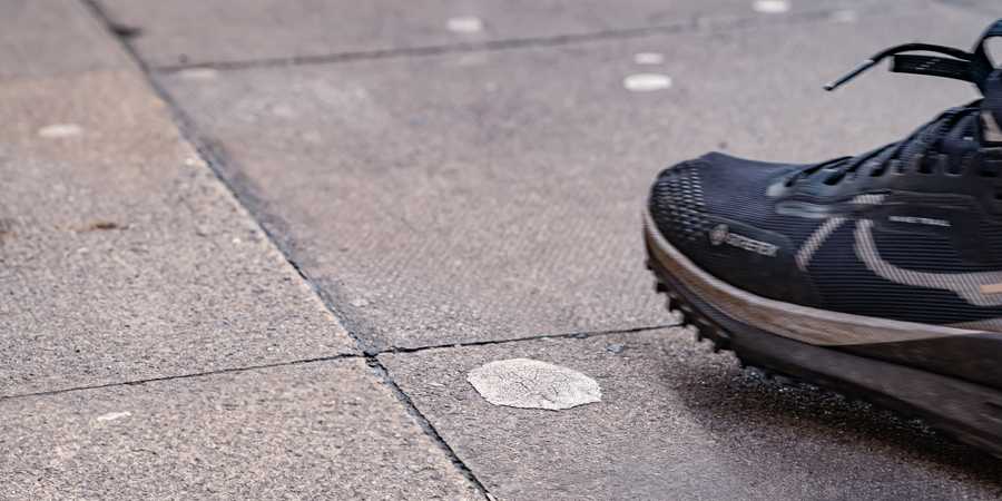 Trainer about to step on some dried chewing gum on the pavement.