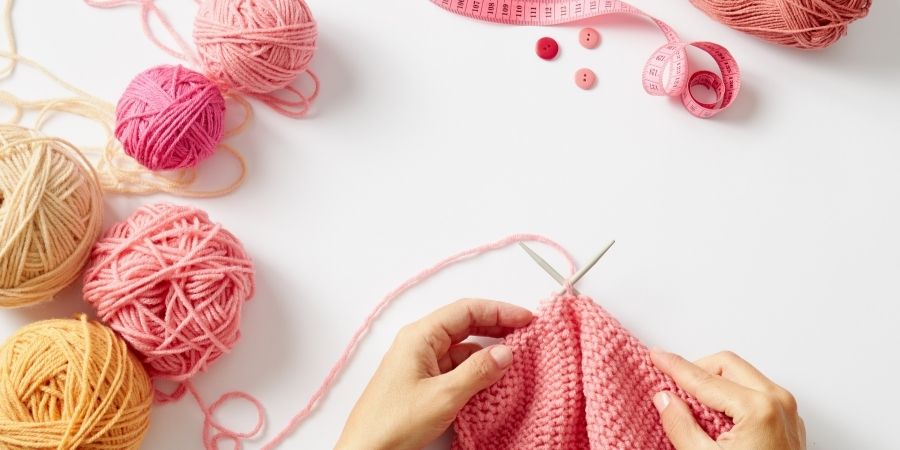 A person knitting on a blank table.