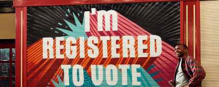 Adult stood in front of sign saying, I am registered to vote.