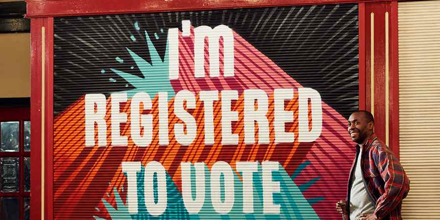 Adult stood in front of sign saying, I am registered to vote.