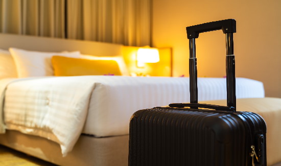 Suitcase in front of a hotel bed.