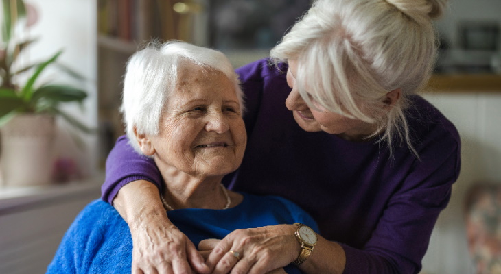 Elderly woman being embraced by a relative.