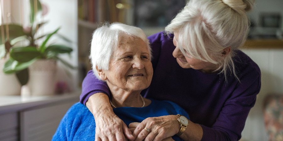 An elderly woman embraced by a relative.
