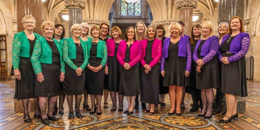 A group of ladies stood in a large ornate room.