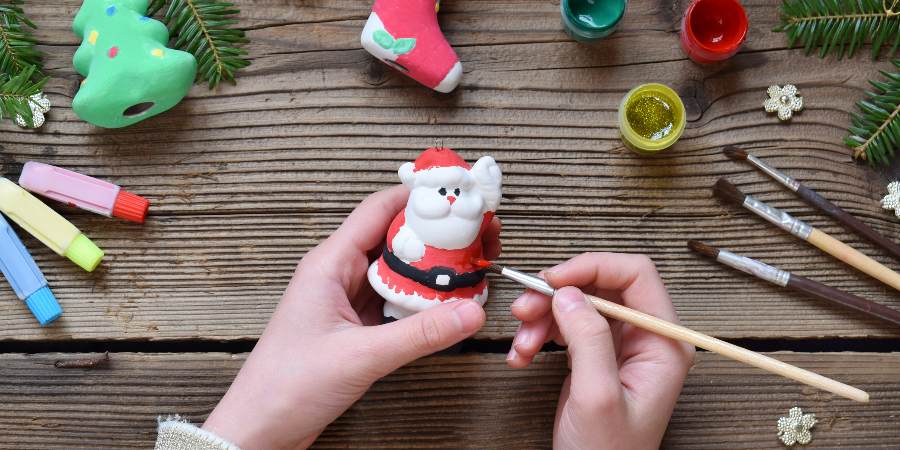 Hands painting a pottery Santa.
