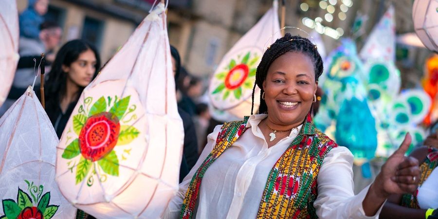 A person smiles while holding paper lanterns.