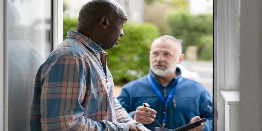 Person with survey chatting with homeowner on their doorstep.