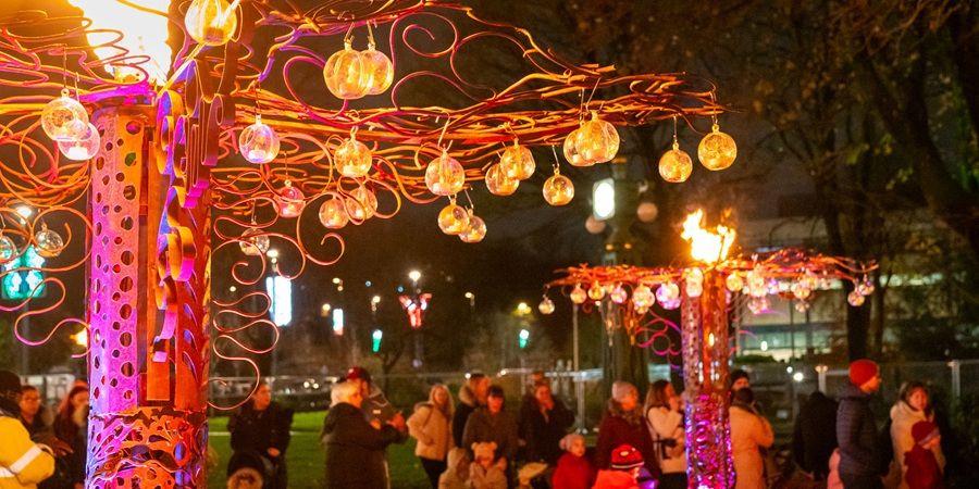 A group of people standing around a tree decorated with lights.