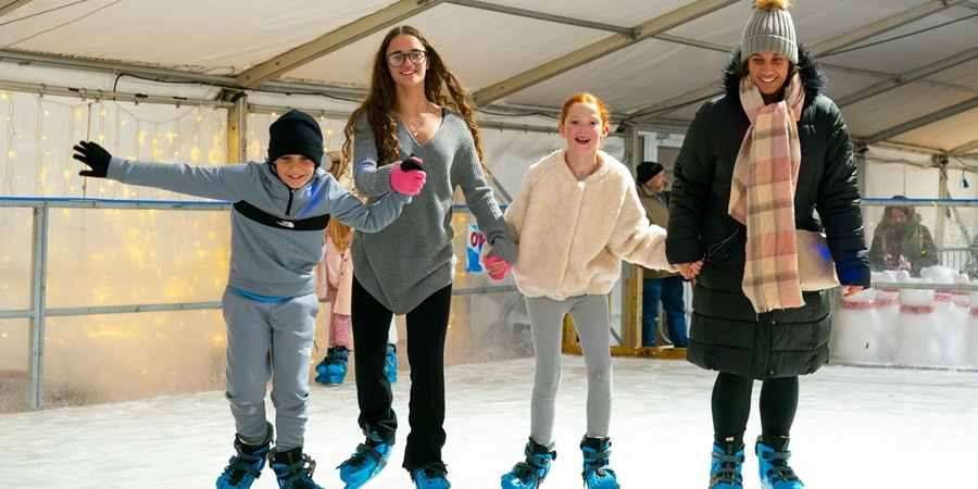 Family skating hand in hand on the ice rink.