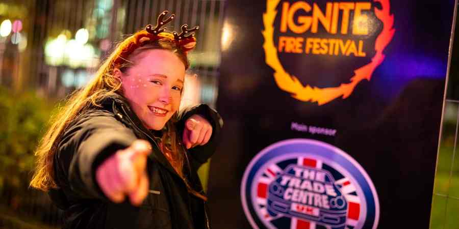 Child stood in front of Ignite sign, pointing at camera.