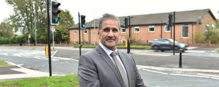 A man in a suit stood by a road.