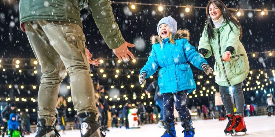 A family skating on an ice rink at night.