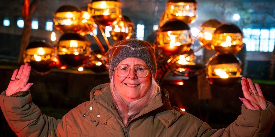 A person wearing winter clothing smiles in front of some lanterns