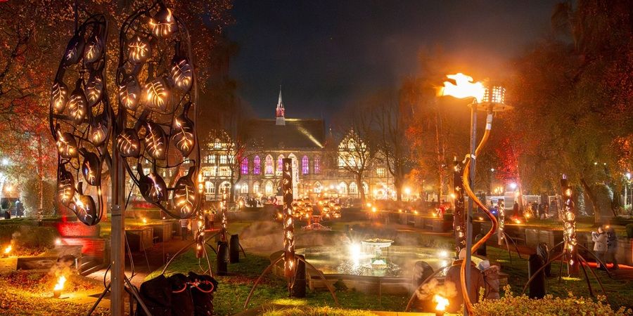 A town hall square full of flaming sculptures and lights.