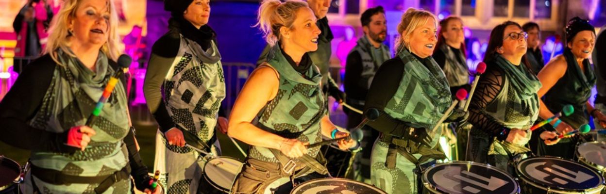 A group wearing matching outfits playing drums.
