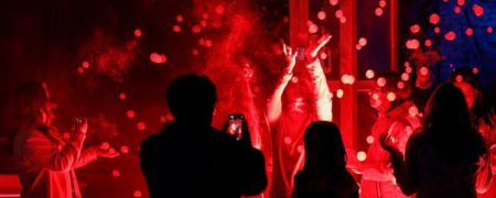 A crowd silhouetted by red flames and lights.