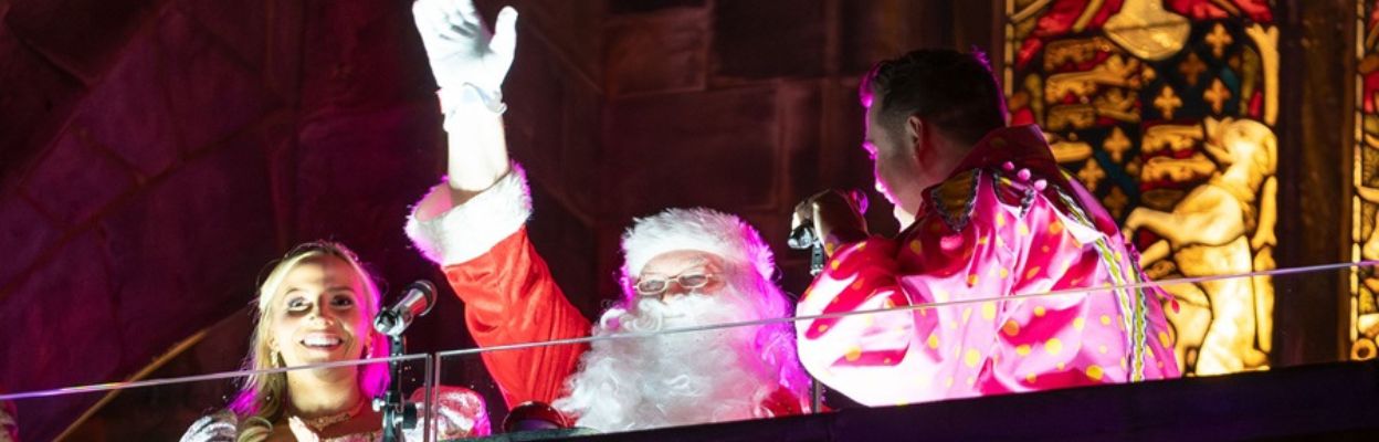 Father Christmas and 2 other people stood on a balcony.