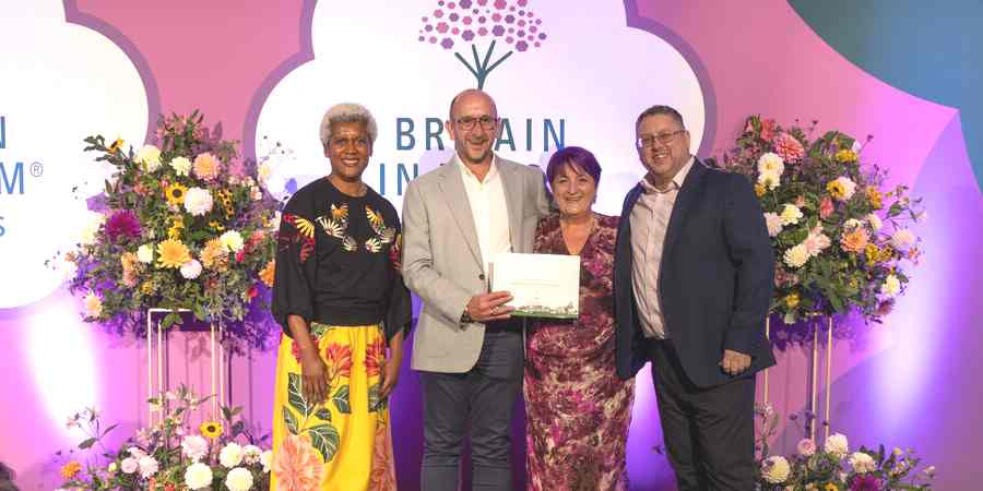 Awards host presents Chairman of Middleton in Bloom, Simon Bennett, Davina Unsworth and Councillor Peter Winkler with their trophy.