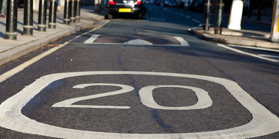 A road hump with a 20mph sign painted on the road in front of it.