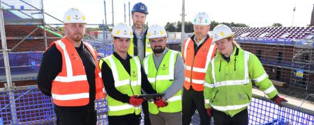 6 people in hi-vis vests and hard hats on a building site.