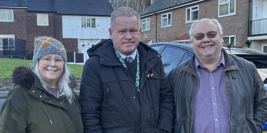 3 people stand in front of houses.