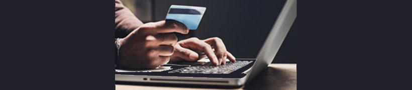 hands holding a card and typing on a laptop