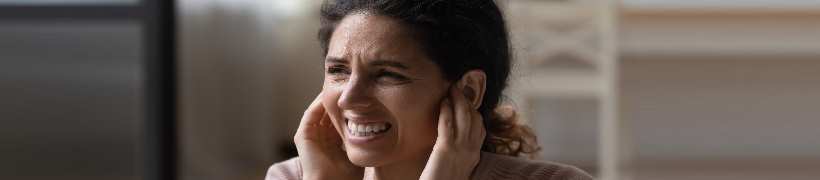 A woman in discomfort covering her ears.