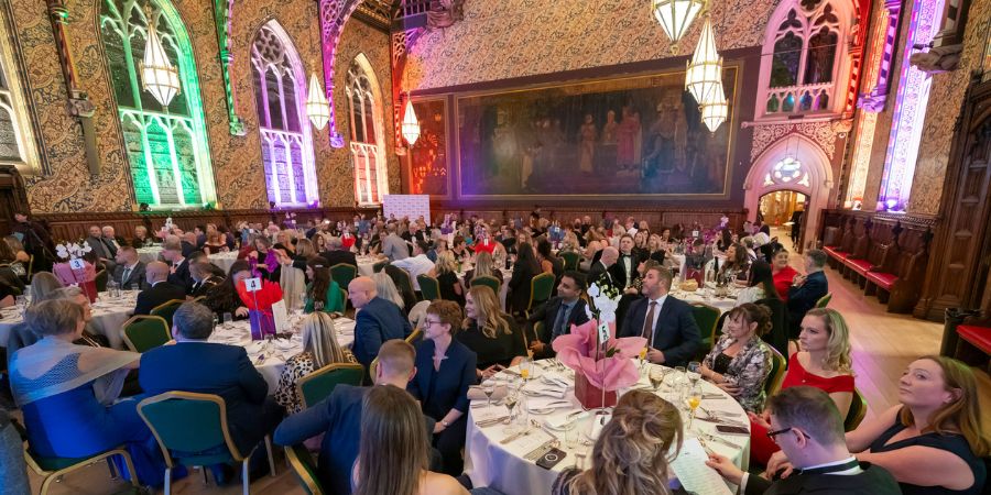 A large group of people sitting at tables in a large hall.