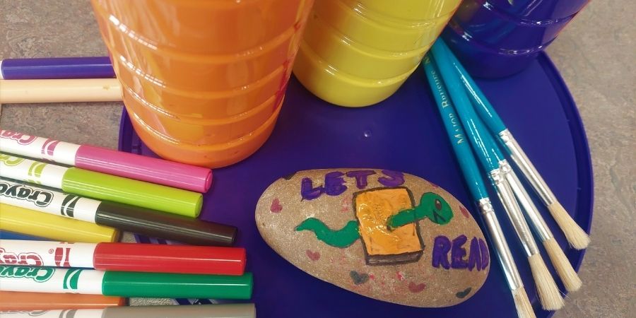 A painted rock that says Lets read.