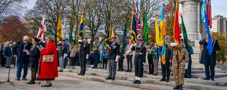 Councillor Neil Emmott at the Rochdale Cenotaph with veterans holding flags.