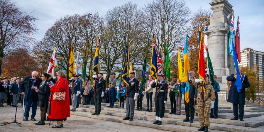A group of people standing in front of a monument with flags.