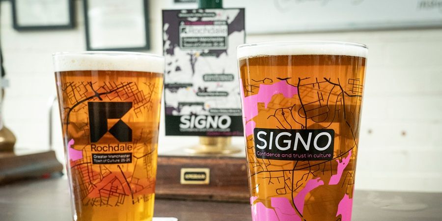2 pints of beer in glasses branded with the word 'Signo'.