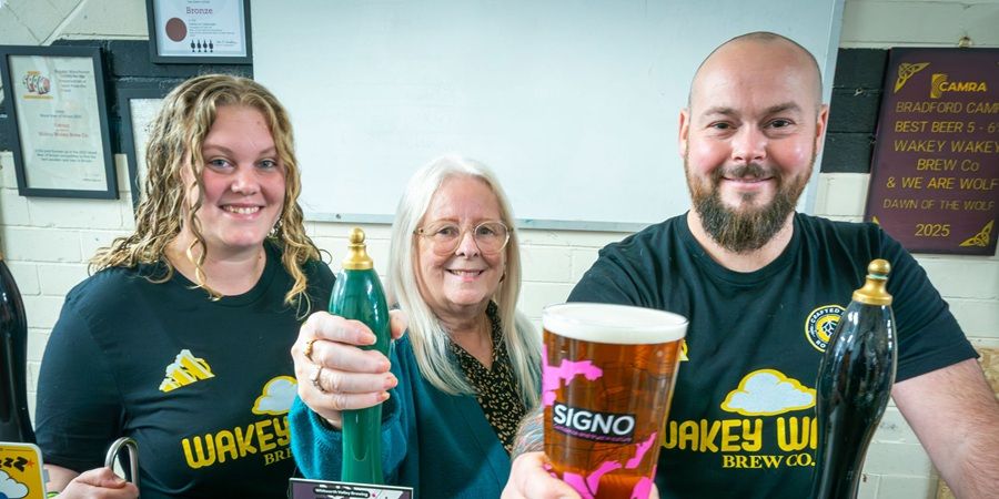 3 people smiling behind a bar.