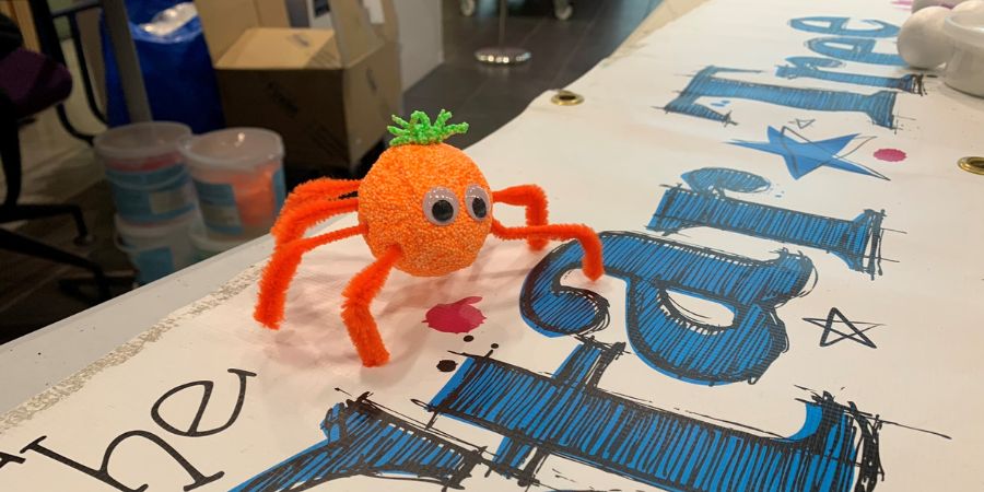 An orange handmade toy spider sitting on top of a banner with the words 'Star Tree' on it.