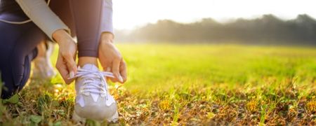 A person in a field tying their shoelaces.