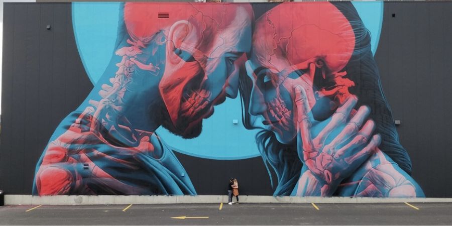 A person standing in front of a large mural of two people.