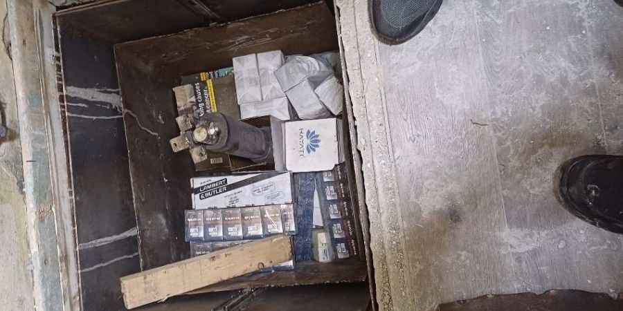 Packets of illegal cigarettes in a hole in a floor.