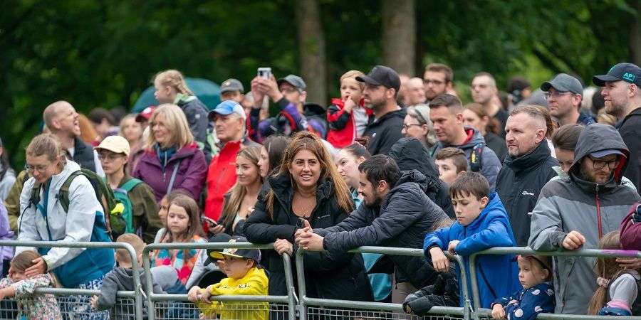 A crowd of people behind a metal fence.