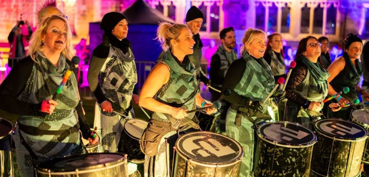 A group of people wearing matching uniforms playing drums.