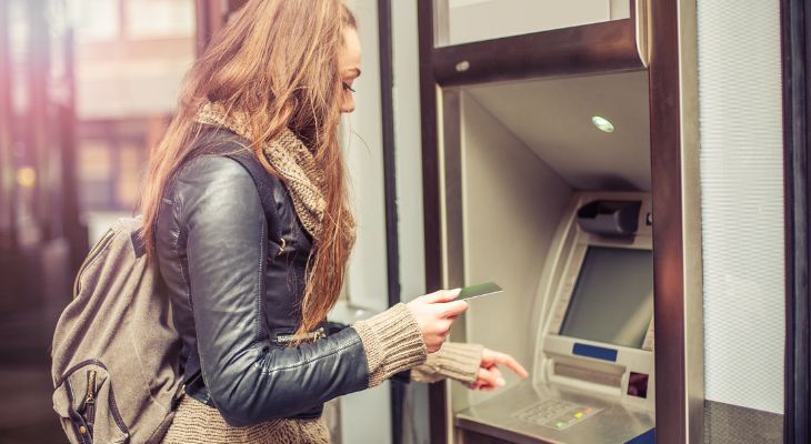 A young person at a cash machine.