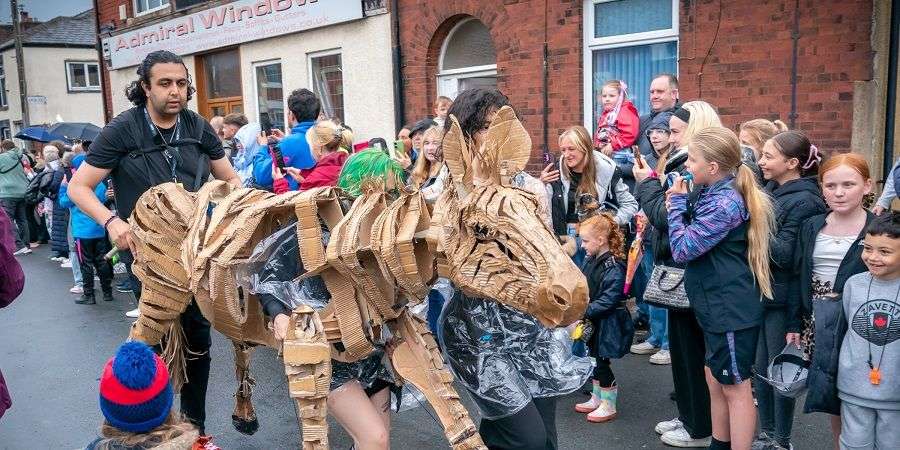 A crowd watching a moving sculpture of a zebra.