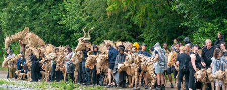 A crowd of people and cardboard sculptures of animals.