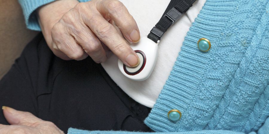 A person pressing their Careline alarm pendant.