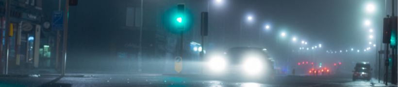 Light from street lights beams across the wet road.