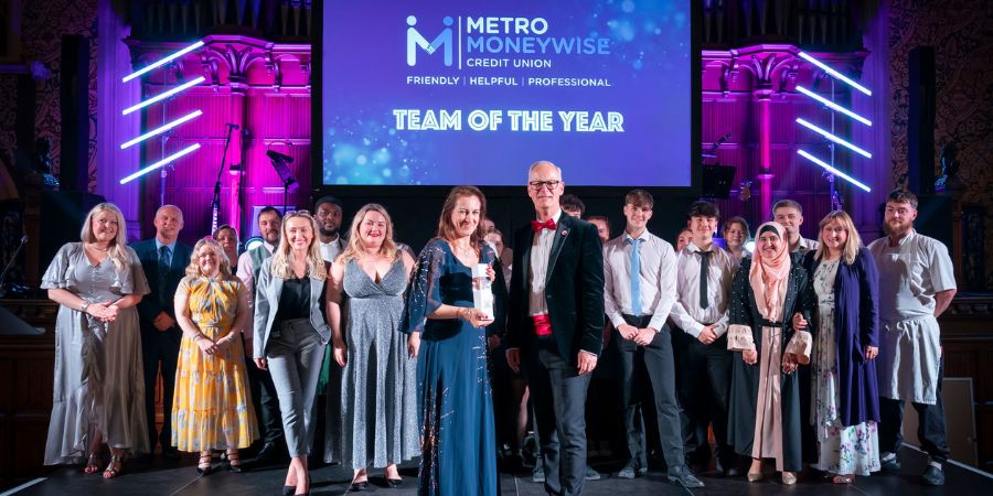 A group of award winners stand on stage in formal attire, celebrating the "Team of the Year".